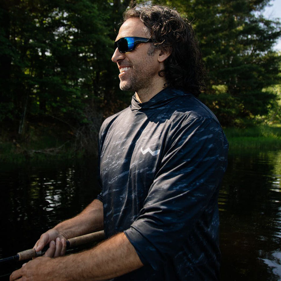 Man wearing black hooded fishing shirt in outdoor water lifestyle scene