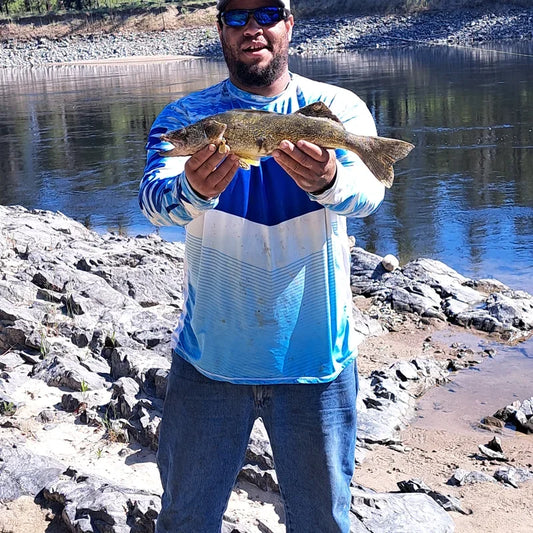 Angler wearing Helios UPF 50+ performance fishing shirt on boat with catch in breezy conditions, demonstrating wind protection and sun defense