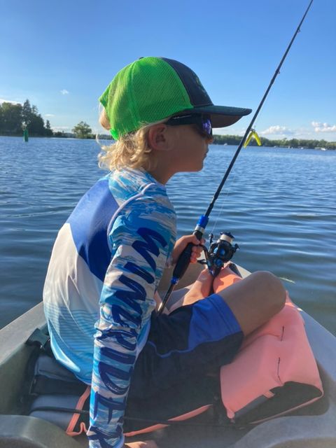 Kid wearing shirt sunglasses and hat fishing