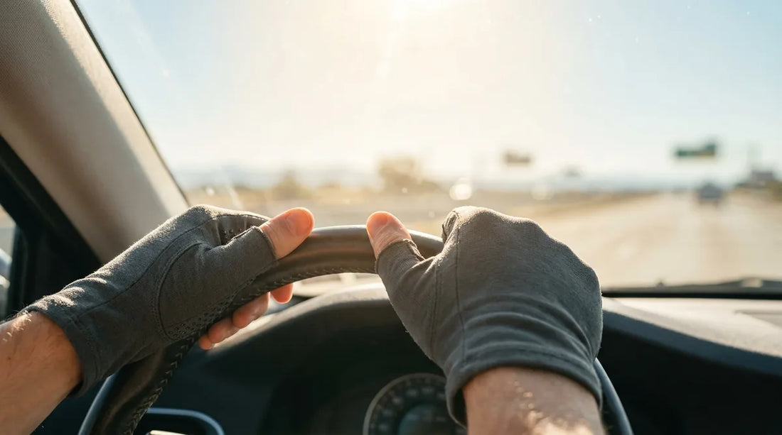 close-up of a driver's hands wearing UPF sun gloves gripping the steering wheel, bright midday sun streaming through the windshield onto an open highway