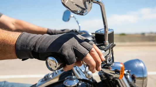 motorcyclist's hands gripping handlebar grips in bright midday sun on an open highway, wearing 3/4-finger UPF sun gloves, cruiser motorcycle visible, clear blue sky