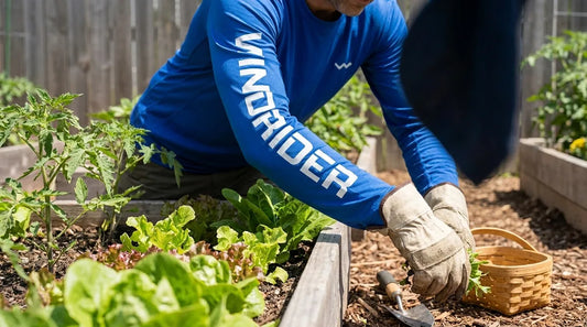gardener bent forward weeding a raised vegetable bed in bright midday sun, wearing a long-sleeve UPF sun shirt with sleeves down to the wrist and gardening gloves