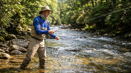 angler wading a clear rocky Appalachian freestone stream, midday summer light, mountains visible in background, wearing UPF long sleeve fishing shirt and neck gaiter, fly rod in hand