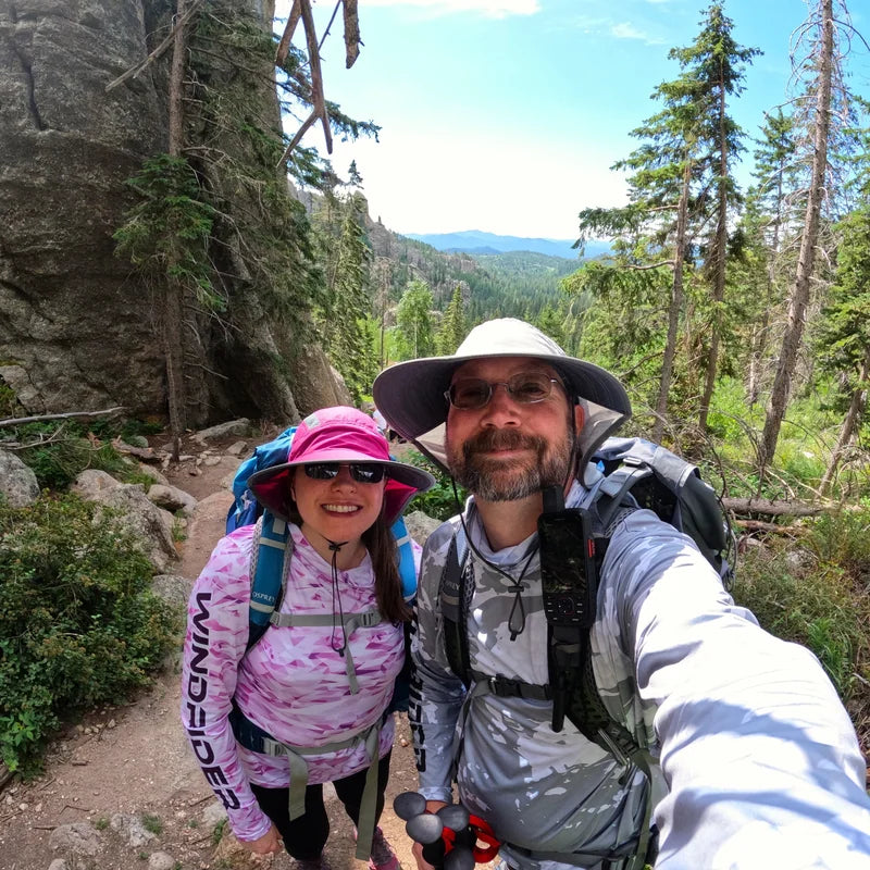 Couple hiking mountain trail in WindRider Helios hooded sun shirts with UPF 50+ protection