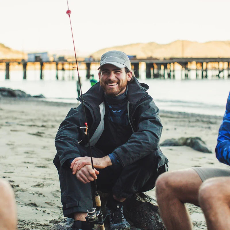 Angler wearing WindRider waterproof rain jacket fishing near pier at beach
