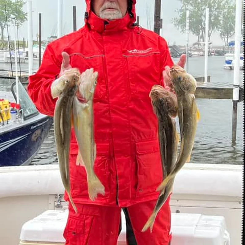 Fisherman wearing full red waterproof rain suit with rain bibs at marina dock on overcast rainy day