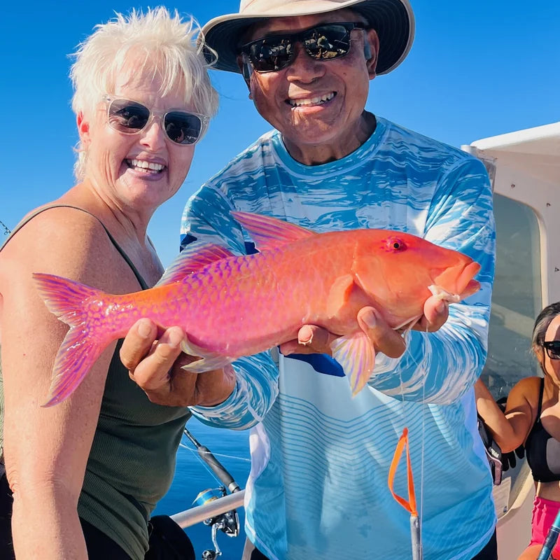Anglers in WindRider Helios sun protection shirts fishing on boat under clear blue sky