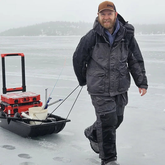 Ice fisherman wearing Boreas insulated cold weather gear on frozen lake displaying walleye catch, demonstrating proper ice fishing line selection