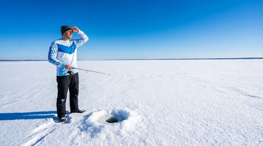 ice fisherman standing on a frozen lake in bright winter sunlight, white snow and ice stretching to the horizon, squinting against the glare, holding a rod over an auger hole