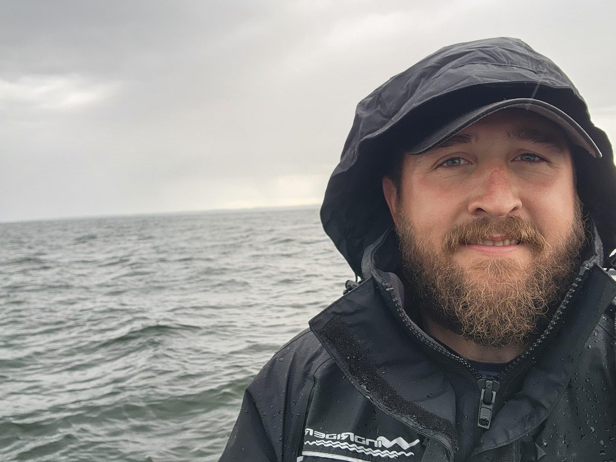 Customer on open water in a storm wearing the black Pro All-Weather jacket with the hood cinched down