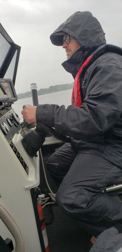 Customer running a boat in the rain in the black suit