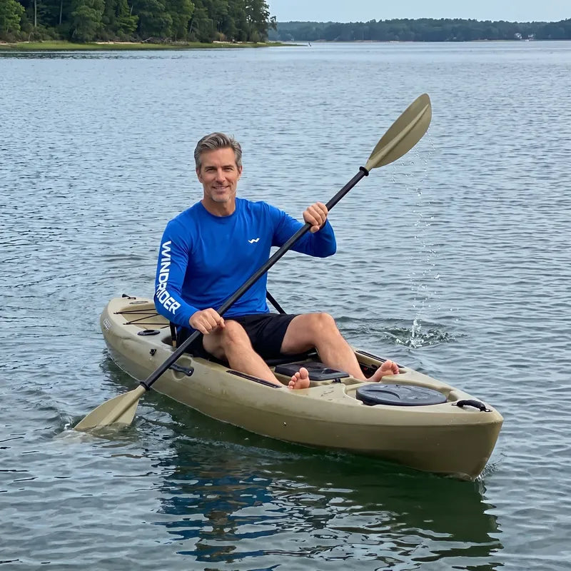 A man paddling a kayak on the bay in the blue Helios sun shirt.