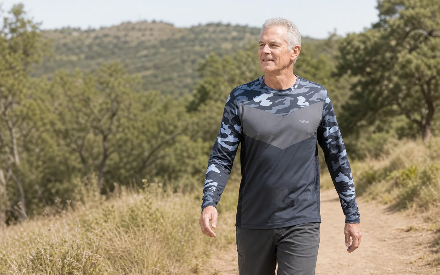 A man wearing a grey-camo Helios Sun Shirt while walking outside.